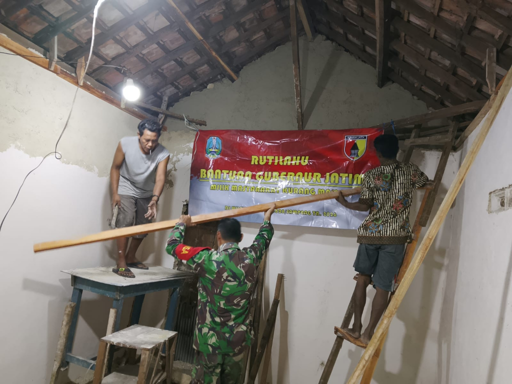 Caption Foto: Personel Babinsa Koramil 0828/03 Omben, Suyitno, turun langsung membantu proses pemasangan plafon rumah